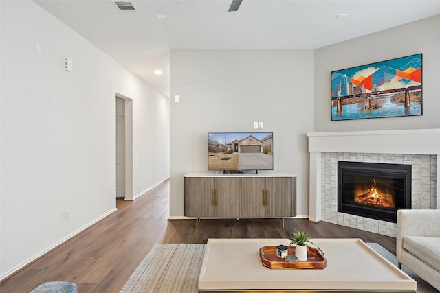 living room featuring a fireplace, baseboards, dark wood-style flooring, visible vents, and recessed lighting