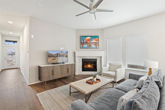 living area with a ceiling fan, a glass covered fireplace, dark wood finished floors, baseboards, and recessed lighting