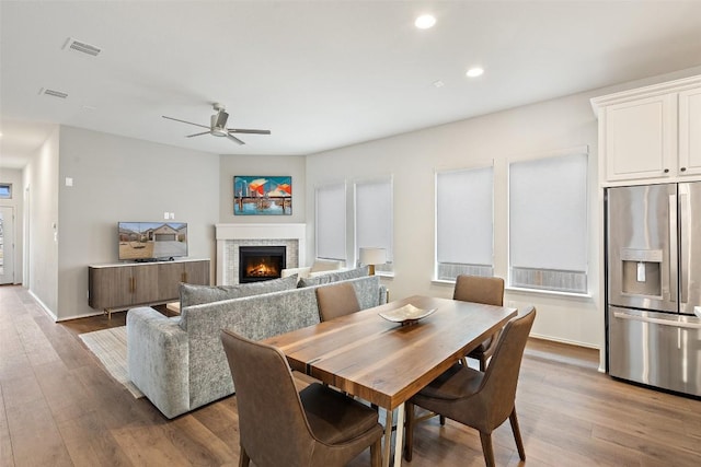dining area featuring visible vents, recessed lighting, a ceiling fan, wood finished floors, and a warm lit fireplace