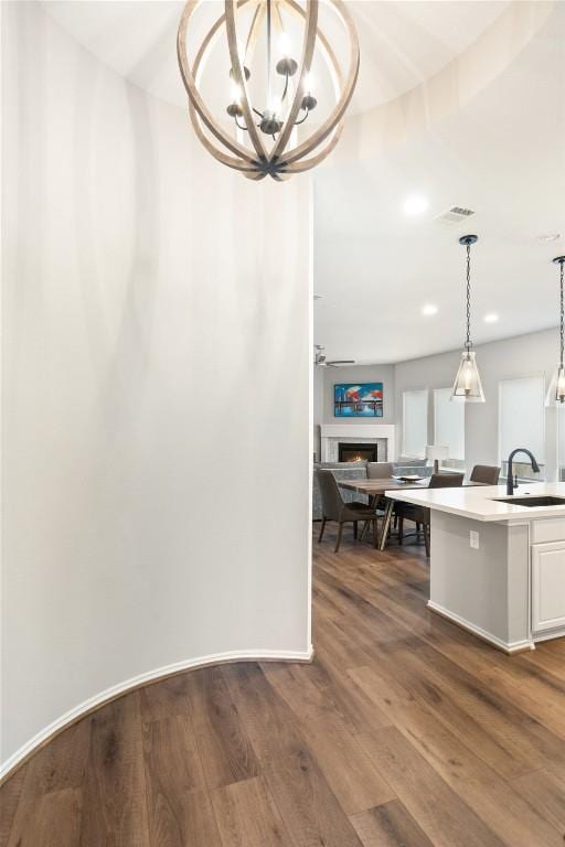 interior space featuring recessed lighting, a warm lit fireplace, visible vents, baseboards, and dark wood-style flooring