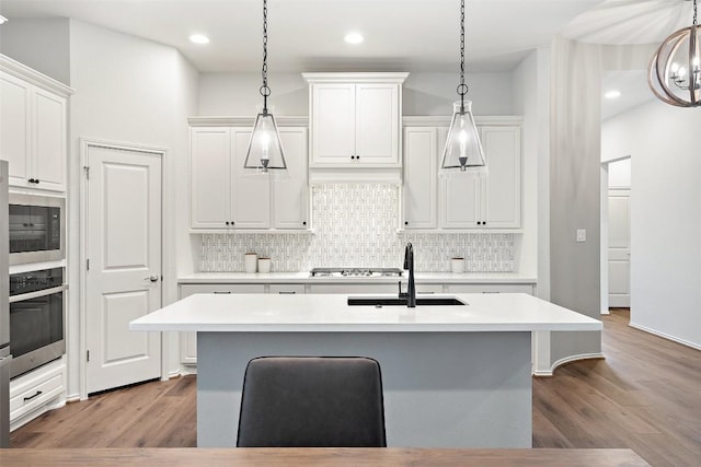 kitchen featuring light countertops, backsplash, oven, and a sink