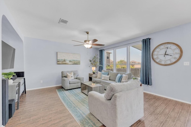 living area featuring light wood-style floors, visible vents, baseboards, and a ceiling fan