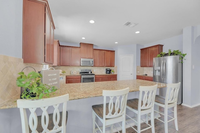 kitchen with tasteful backsplash, a peninsula, visible vents, and stainless steel appliances