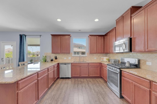 5812 Pescia St, Round Rock, TX 78665 - kitchen with stainless steel appliances, a sink, a peninsula, light wood-type flooring, and light stone countertops