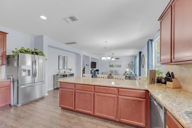 5812 Pescia St, Round Rock, TX 78665 - kitchen with appliances with stainless steel finishes, a chandelier, a peninsula, backsplash, and light wood-type flooring