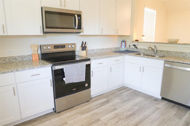 70 Snowy Plover Ln, Leander, TX 78641 - kitchen featuring stainless steel appliances, a sink, light wood-type flooring, and white cabinets
