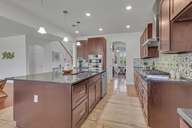 kitchen featuring a sink, arched walkways, stainless steel appliances, backsplash, and visible vents