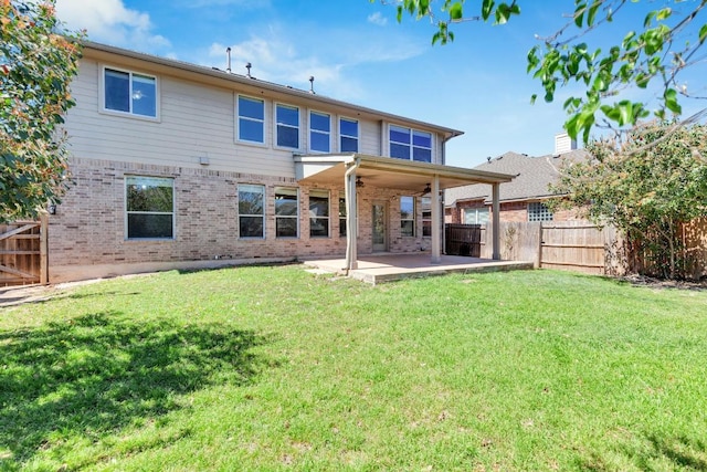 back of property with a fenced backyard, brick siding, a ceiling fan, a patio area, and a yard
