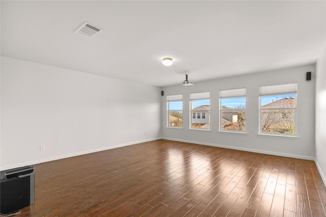 spare room with baseboards, dark wood-style flooring, and visible vents