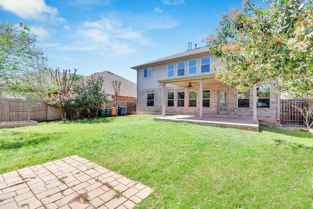 rear view of property with ceiling fan, a fenced backyard, brick siding, a patio area, and a yard
