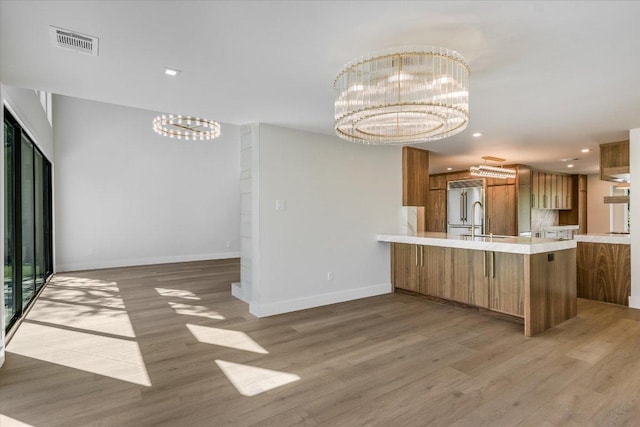 6304 Lost Horizon Dr, Austin, TX 78759 - kitchen featuring a chandelier, high end refrigerator, brown cabinets, light wood-style floors, and a peninsula