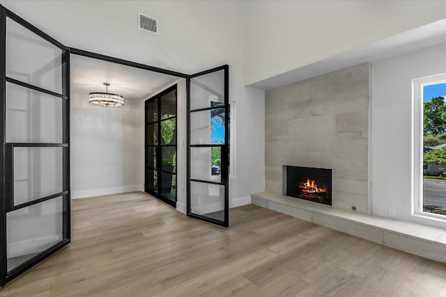 6304 Lost Horizon Dr, Austin, TX 78759 - unfurnished living room featuring a tile fireplace, a chandelier, wood finished floors, and baseboards