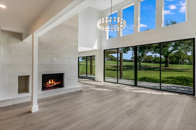6304 Lost Horizon Dr, Austin, TX 78759 - unfurnished living room featuring a towering ceiling, a fireplace, wood finished floors, and a chandelier