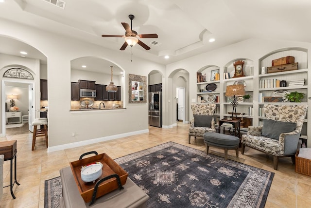 215 Choke Canyon Ln, Georgetown, TX 78628 - living room with built in shelves, ceiling fan, arched walkways, a tray ceiling, and recessed lighting