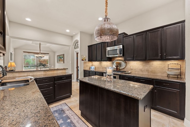 215 Choke Canyon Ln, Georgetown, TX 78628 - kitchen featuring stainless steel microwave, decorative backsplash, recessed lighting, light stone countertops, and decorative light fixtures