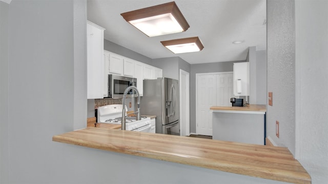 812 Saunders Dr, Round Rock, TX 78664 - kitchen featuring appliances with stainless steel finishes, white cabinets, backsplash, light countertops, and a peninsula