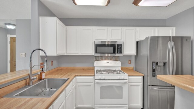 812 Saunders Dr, Round Rock, TX 78664 - kitchen with appliances with stainless steel finishes, butcher block counters, white cabinets, and decorative backsplash