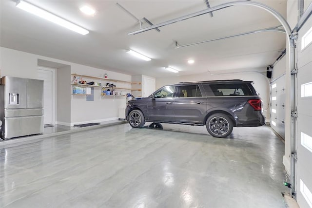 garage with baseboards and stainless steel refrigerator with ice dispenser