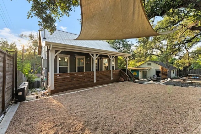 exterior space featuring metal roof, fence, and covered porch