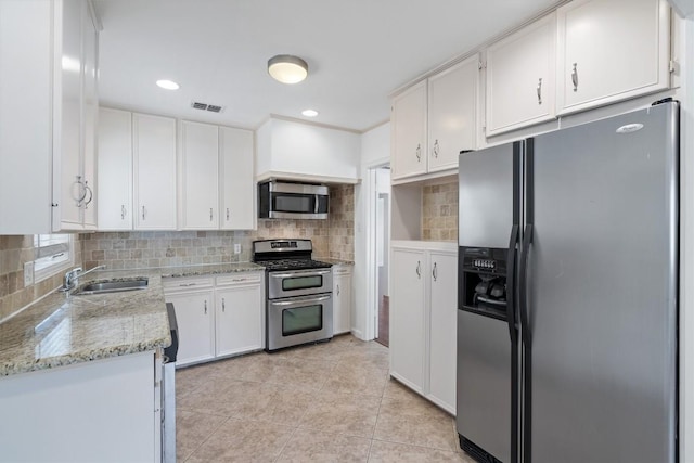 1905 Robinhood Trl, Austin, TX 78703 - kitchen with appliances with stainless steel finishes, white cabinets, backsplash, light stone countertops, and light tile patterned floors