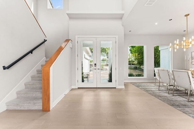 entrance foyer featuring an inviting chandelier, french doors, stairs, and visible vents