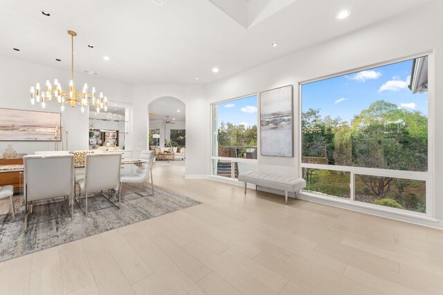 dining space featuring recessed lighting, arched walkways, a notable chandelier, and a wealth of natural light