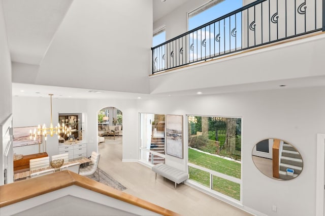 interior space featuring a high ceiling, a notable chandelier, recessed lighting, baseboards, and wood finished floors