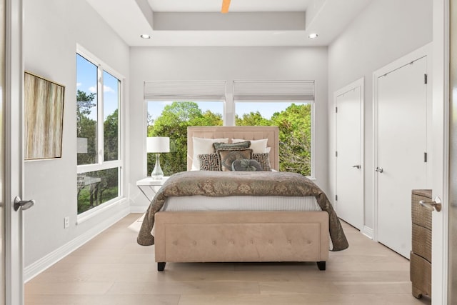 bedroom with light wood-style floors, multiple closets, baseboards, and recessed lighting