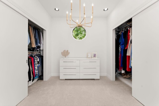 spacious closet featuring an inviting chandelier and light colored carpet