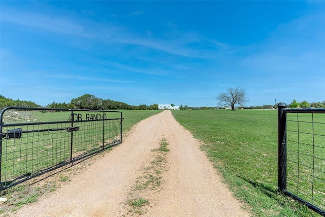 290 County Road 207, Liberty Hill, TX 78642 - view of dirt / gravel driveway featuring a view of countryside, a gate, and a gated entry