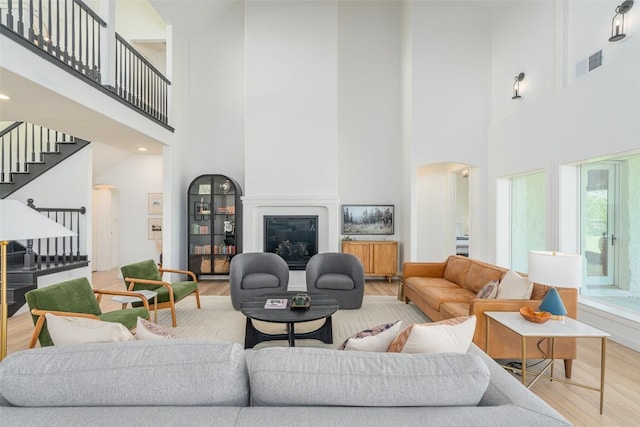 290 County Road 207, Liberty Hill, TX 78642 - living room featuring arched walkways, wood finished floors, a towering ceiling, stairs, and a glass covered fireplace