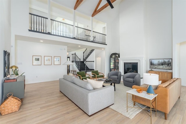 290 County Road 207, Liberty Hill, TX 78642 - living room featuring high vaulted ceiling, light wood-type flooring, stairs, a glass covered fireplace, and beam ceiling
