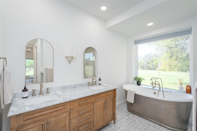 290 County Road 207, Liberty Hill, TX 78642 - bathroom featuring healthy amount of natural light, double vanity, a freestanding tub, baseboards, and recessed lighting