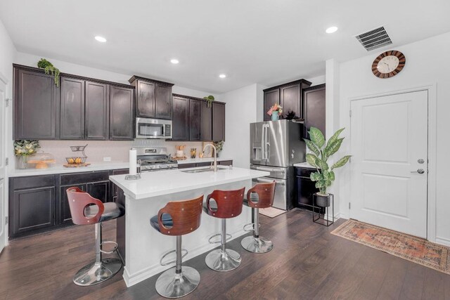 112 Gracie Way, Hutto, TX 78634 - kitchen featuring appliances with stainless steel finishes, dark wood finished floors, a kitchen bar, light countertops, and recessed lighting