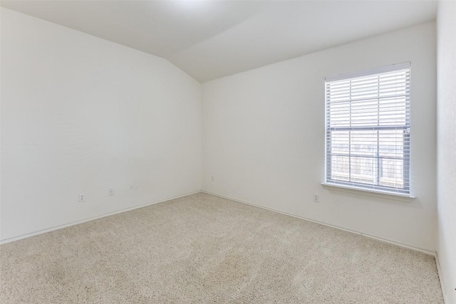 carpeted empty room with baseboards and lofted ceiling