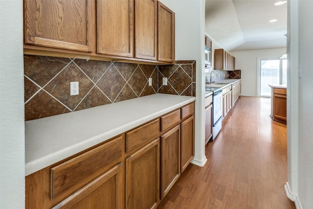 kitchen featuring electric stove, brown cabinets, vaulted ceiling, and wood finished floors