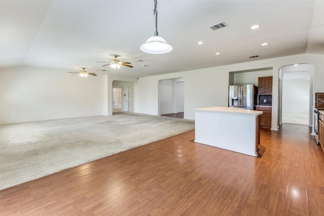 kitchen with arched walkways, stainless steel refrigerator with ice dispenser, visible vents, and a center island