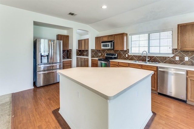 kitchen with visible vents, a sink, light wood-type flooring, brown cabinets, and stainless steel appliances