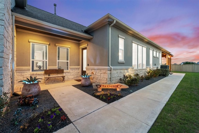 view of property exterior with fence, stone siding, and stucco siding