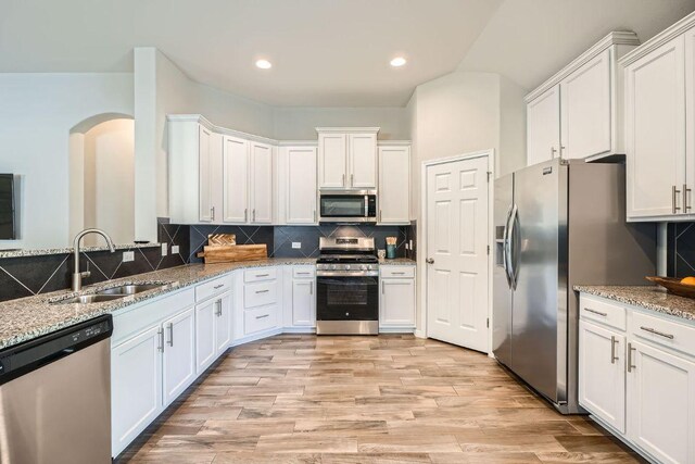 2013 Garretts Way, Manchaca, TX 78652 - kitchen featuring appliances with stainless steel finishes, a sink, arched walkways, white cabinetry, and recessed lighting