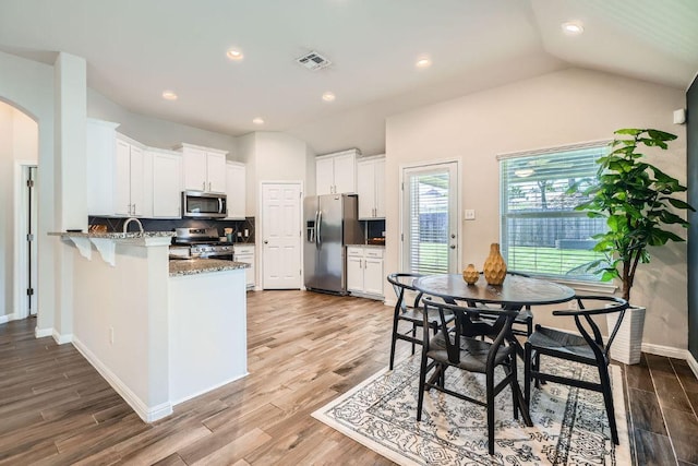 2013 Garretts Way, Manchaca, TX 78652 - kitchen featuring appliances with stainless steel finishes, a peninsula, white cabinets, backsplash, and stone counters