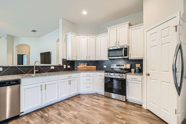2013 Garretts Way, Manchaca, TX 78652 - kitchen with appliances with stainless steel finishes, a sink, arched walkways, white cabinets, and stone countertops