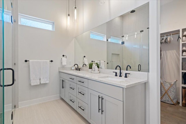7009 Zachary Dr, Austin, TX 78724 - bathroom featuring a walk in closet, double vanity, a stall shower, and plenty of natural light