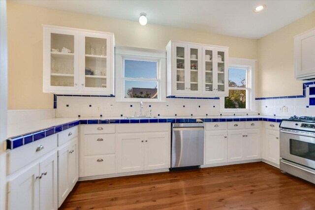 508 S Walnut St, Georgetown, TX 78626 - kitchen with stainless steel appliances, tile countertops, white cabinetry, decorative backsplash, and a sink