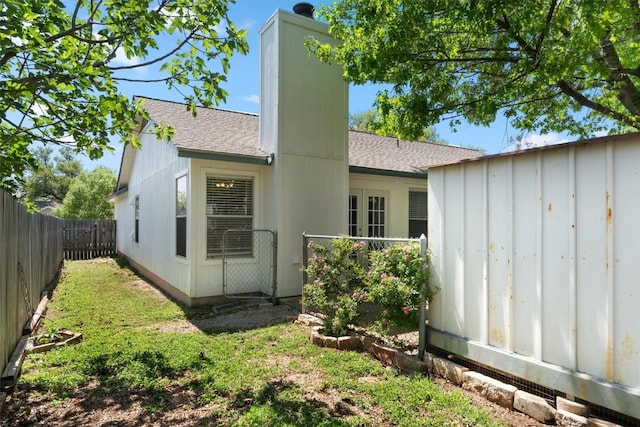 4902 Ganymede Dr, Austin, TX 78727 - rear view of house with a shingled roof, a fenced backyard, board and batten siding, and a chimney