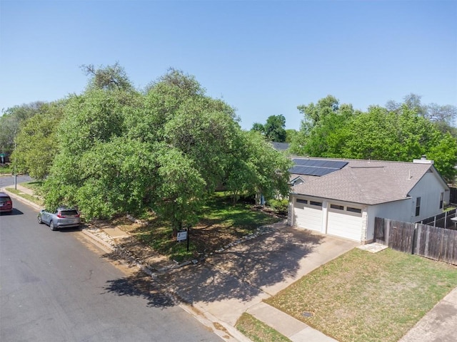 4902 Ganymede Dr, Austin, TX 78727 - view of front of home featuring roof mounted solar panels, a garage, driveway, and roof with shingles