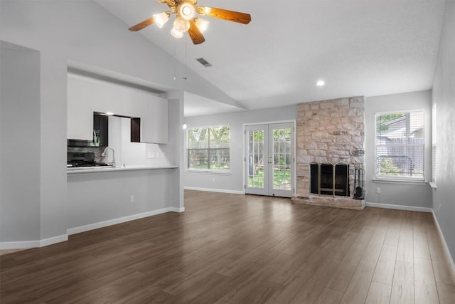 4902 Ganymede Dr, Austin, TX 78727 - unfurnished living room with ceiling fan, vaulted ceiling, baseboards, dark wood finished floors, and a stone fireplace