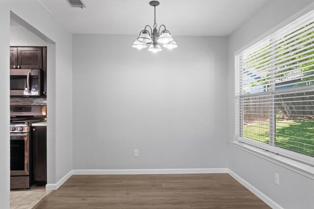 4902 Ganymede Dr, Austin, TX 78727 - unfurnished dining area with a chandelier, light wood-type flooring, and baseboards