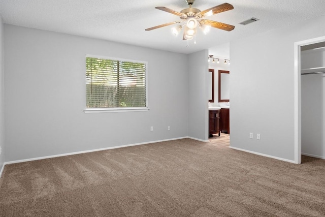 4902 Ganymede Dr, Austin, TX 78727 - unfurnished bedroom with carpet floors, a closet, connected bathroom, a ceiling fan, and a textured ceiling