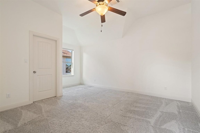 carpeted empty room featuring ceiling fan, vaulted ceiling, and baseboards